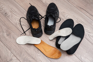 Adult and children orthopedic insoles on the room floor and in footwear showing family foot care and early valgus prevention