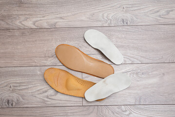 Adult and children orthopedic insoles on the room floor and in footwear showing family foot care and early valgus prevention
