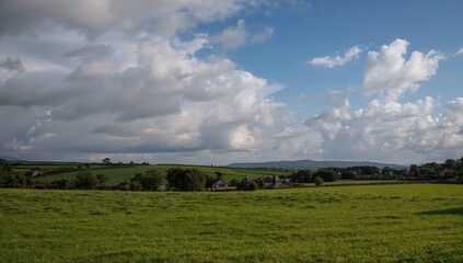Obraz premium Sky Filled With Cumulus Clouds Above A Quaint Village During A Summer Evening, Ideal For Seasonal Reflection