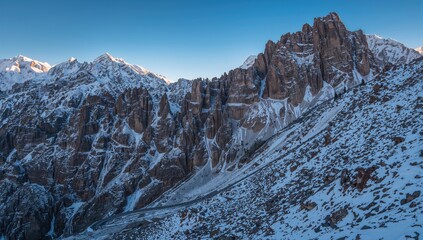 Vertical image of rugged, snow-capped mountains along a highway, highlighting erosion risk