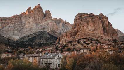 Naklejka premium Quaint village nestled at the base of a mountain, showcasing seasonal change