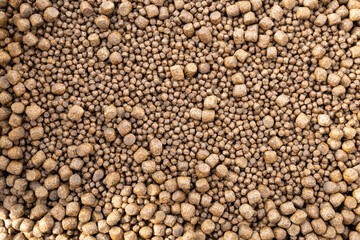 Bulk brown food pellets of different sizes and same form.