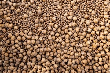 Bulk brown food pellets of different sizes and same form.