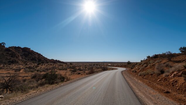 A winding road traverses a desert landscape under a clear sky, highlighting erosion risk - Powered by Adobe