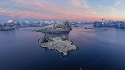 Aerial perspective of icy islands and mountains over a turquoise ocean under pink-hued clouds at sunset, winter scenery