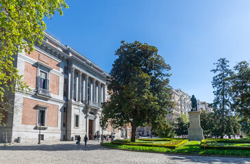 El Prado Museum on a sunny spring morning, showcasing elegant neoclassical architecture, grand statues, and lush green trees framing its bright, inviting façade with added charm