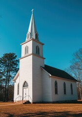Fototapeta premium Classic white wooden country church with a tall steeple against a bright blue sky, typical southern religious architecture seen here, traditional, spiritual, chapel