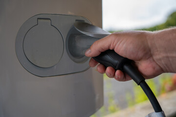 Close-up of hands connecting cables to an electric vehicle charger