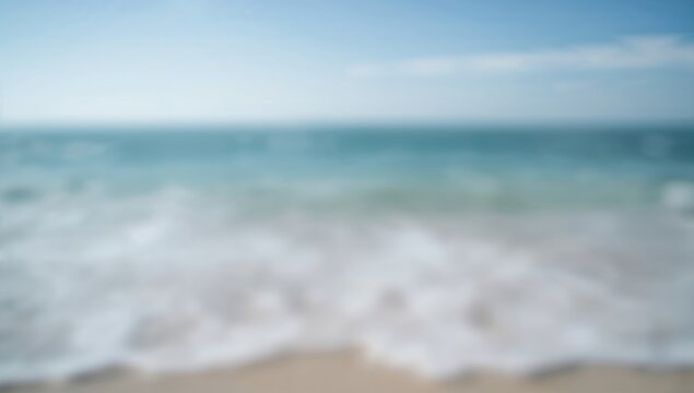 A blurred image of a seashore shows the tranquil essence of the ocean, with soft waves merging into the sky, evoking serenity