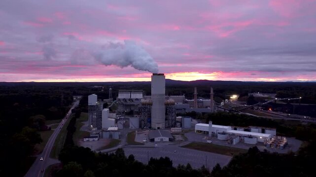 Coal power plant in Catawba on Lake Norman emits steam into a colorful sunset sky, aerial cinematic video.