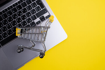 Miniature metal shopping basket placed on a laptop keyboard with copy space. E-Commerce and online shopping concept