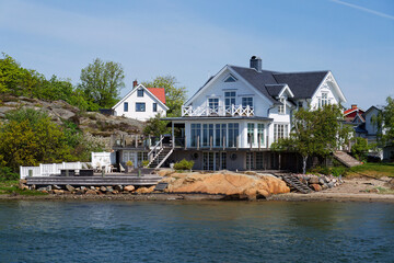 Obraz premium Houses on the rocks of Saltholmen peninsula on shore of Alvsborgsfjorden harbour, Alvsborg district, sunny day, Gothenburg, Sweden
