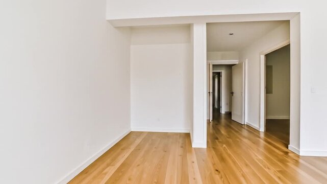 Interior shot of a modern apartment with wood flooring and white walls, leading to a hallway