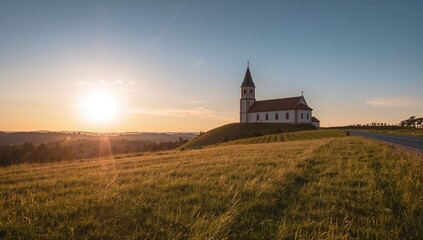 Fototapeta premium A chapel situated on a hillside with a summer view illuminated by golden sunset light, seasonal change