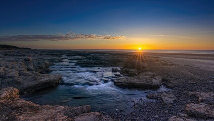 A rocky coastline with a flowing stream cascading over boulders, highlighting erosion risk