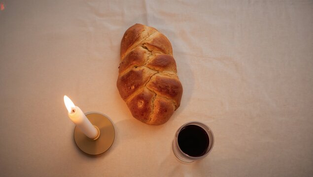 Challah bread, wine, and candles arranged in a flat lay, symbolizing tradition and celebration