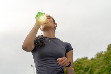 Woman drinking refreshing sports drink, restoring energy after intense fitness activity