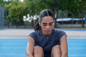 Woman feeling worn out from physical exercise at track and field facility