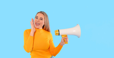 Woman in yellow sweater using megaphone against blue background