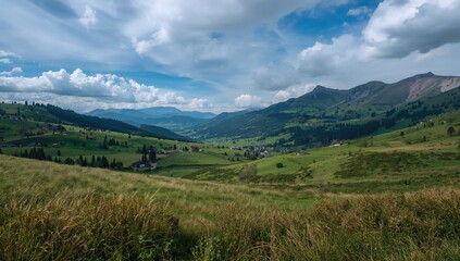 Fototapeta premium Valley view featuring meadows and bushes, hiking trail winding through fields, homes nestled below mountains, seasonal change