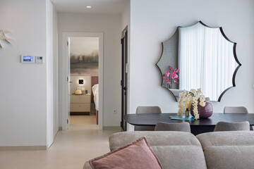 Cozy modern living space with mirror, dining table and view into bedroom interior © Tom