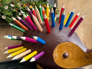 a colorful decorative sculpture resembling a hedgehog, with its spikes made from large, vibrant wooden pencils. The playful artwork has a brown body and a wooden face