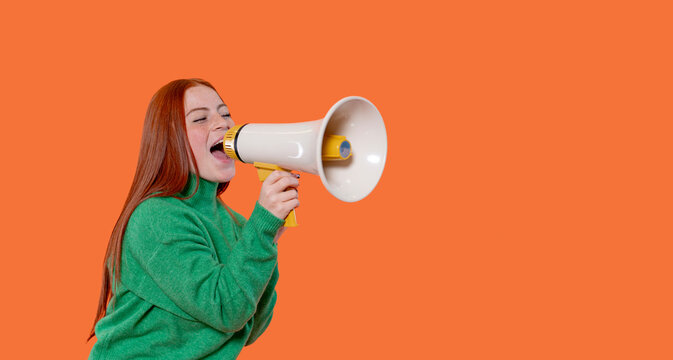 Woman uses megaphone against bright orange background during lively protest