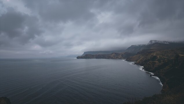 A darkened sky looms over the ocean, with rocky formations and hills in the vicinity, erosion risk