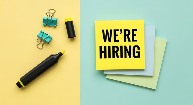 We're hiring" message on yellow sticky note with office supplies