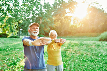 Smiling active senior people stretching and exercising together in the park, healthy lifestile workout fitness training class