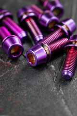 Pink anodized titanium alloy screws on a black textured background