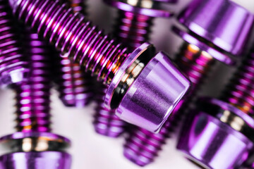 A scattering of titanium bolts in the macro are arranged on a snow-white background