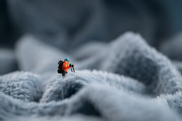 A figurine of a miniature mountain climber, set on a soft fleece surface that mimics a snow-covered landscape
