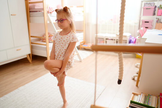 Little girl practicing yoga in cozy bedroom