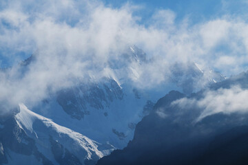 Silhouettes of snow-capped mountains and low clouds at dawn