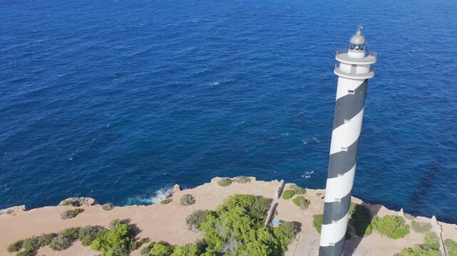 Aerial View of the Striped Moscarter Lighthouse (Far de sa Punta des Moscarter) on the Rugged Northern Cliffs of Ibiza, Spain	