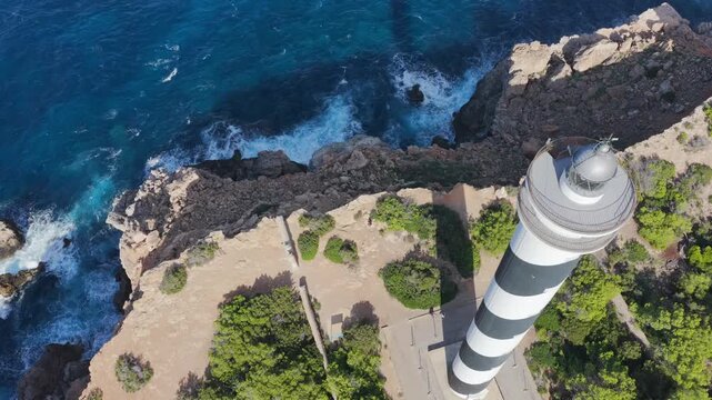 Aerial View of the Striped Moscarter Lighthouse (Far de sa Punta des Moscarter) on the Rugged Northern Cliffs of Ibiza, Spain	