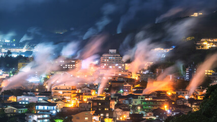 Beppu town with motion steam of hot spring bath houses at night, Oita