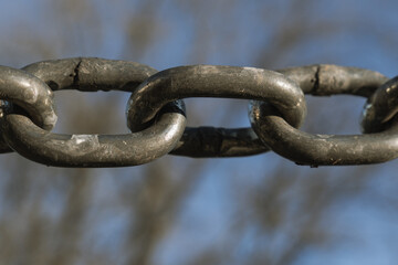 Close-Up of Weathered Metal Chain Links Against Soft Blue Sky
