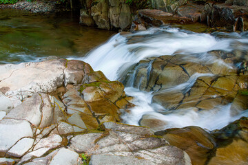 A mountain stream among pebbles with small waterfalls
