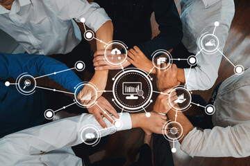 A diverse group of professionals engages in teamwork, with hands joined symbolizing collaboration....