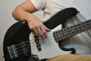 A man playing a black electric bass guitar