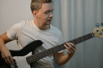 A man playing a black electric bass guitar