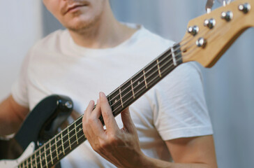 A man playing a black electric bass guitar