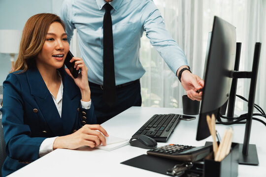 Businesswoman calling with business partner on mobile phone while calculating stock exchange value data with man in casual pointing on pc, analyzing company value sell or buy on up to date. Infobahn. - Powered by Adobe