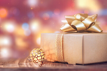 festive box with a golden bow and a glowing bell on a background of soft multicolored side