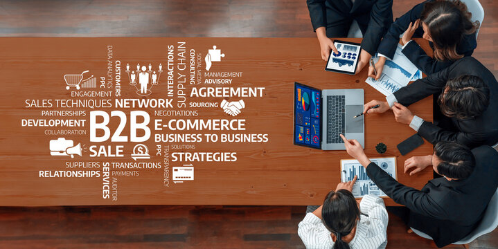 A top-down view of professionals in a business meeting discussing B2B strategies, analyzing data on laptops and presenting charts to enhance collaboration and growth. Amity