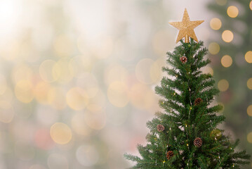 Christmas tree with golden star topper surrounded by warm bokeh lights creating a festive holiday atmosphere for seasonal decoration themes winter celebration visuals cozy xmas background