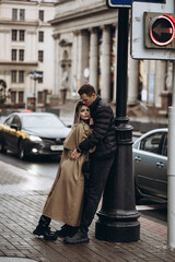 Obraz premium Couple enjoying a moment of affection on a busy city street near a traffic light during a chilly day