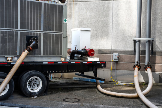 temporary pumping system mounted on trailer set up outside a building, likely for fluid transfer or a bypass operation